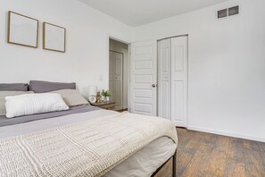 A bedroom with a bed, a nightstand, a door, and two framed pictures on the wall. - 3/4 Mi to Eat Street! Midtown Mini Hideaway (Minneapolis)