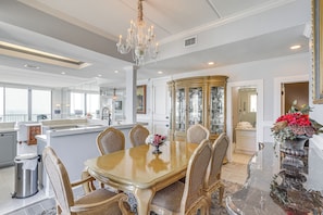 A dining area with a chandelier, a glass cabinet, and a dining table with chairs. - Penthouse w/ Beach Access: Suntide III - Unit 1101 (South Padre Island)