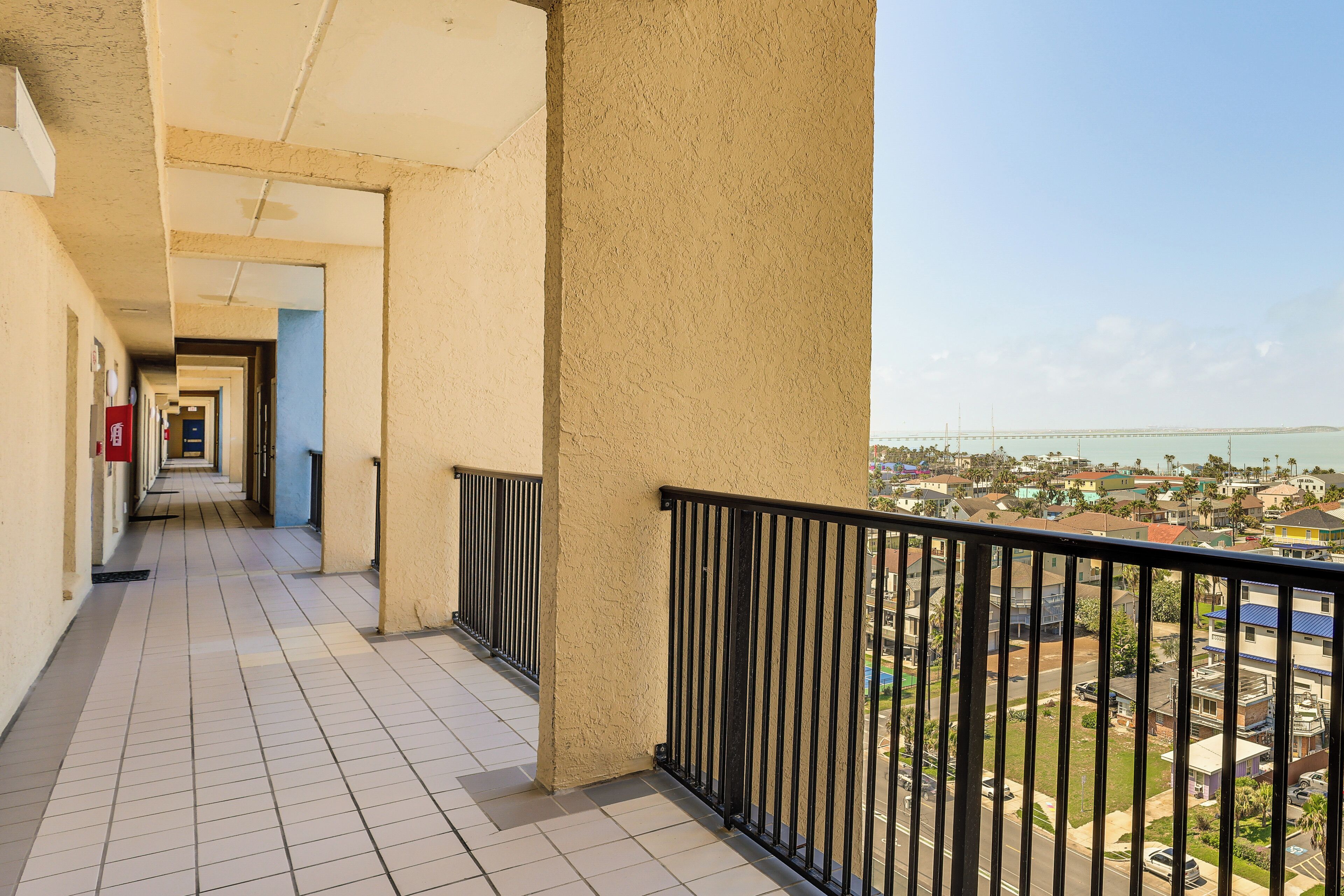 A corridor with a view of a residential area and a bridge in the distance.