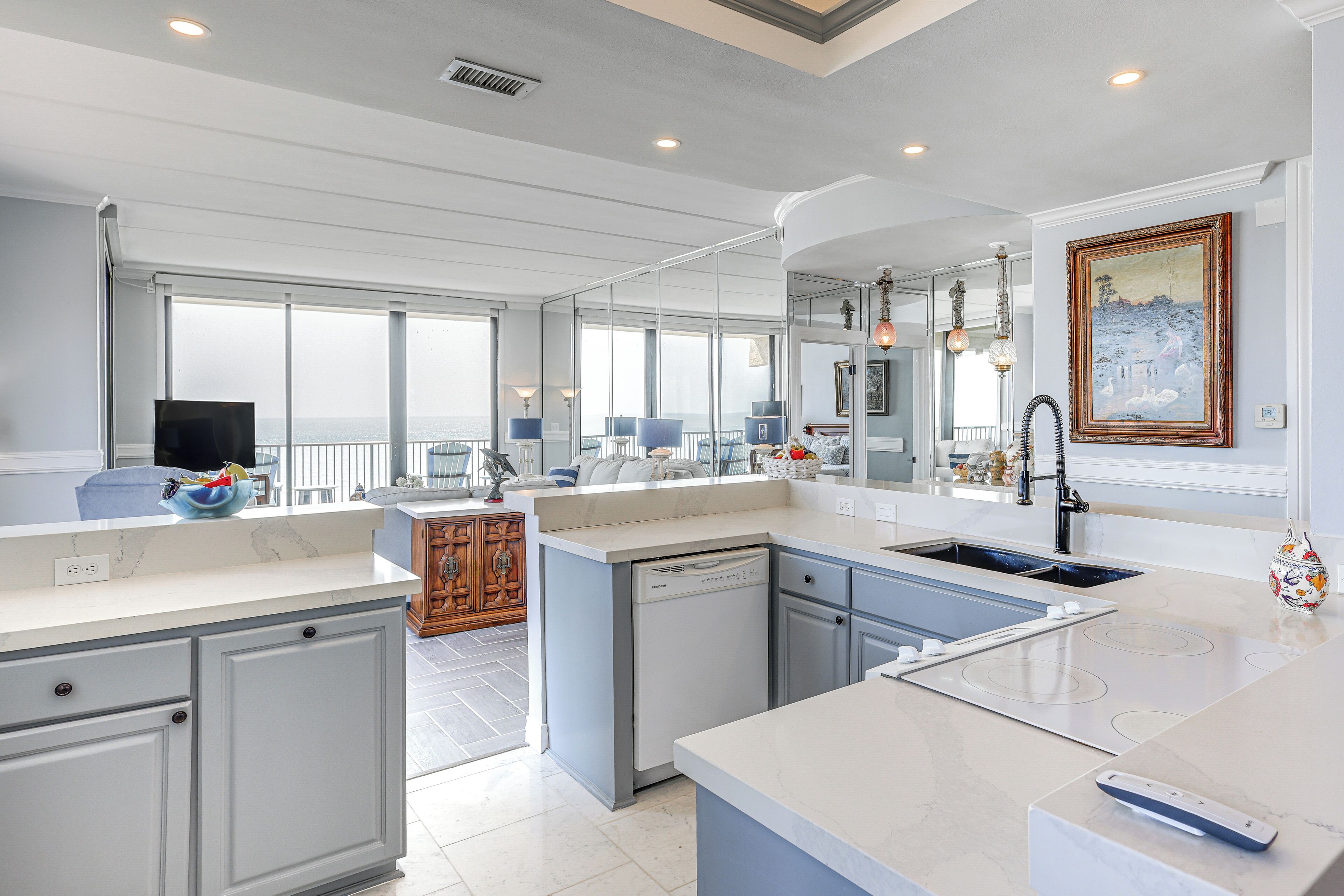 Una cocina moderna con una isla grande, lavavajillas integrado y vista al mar.