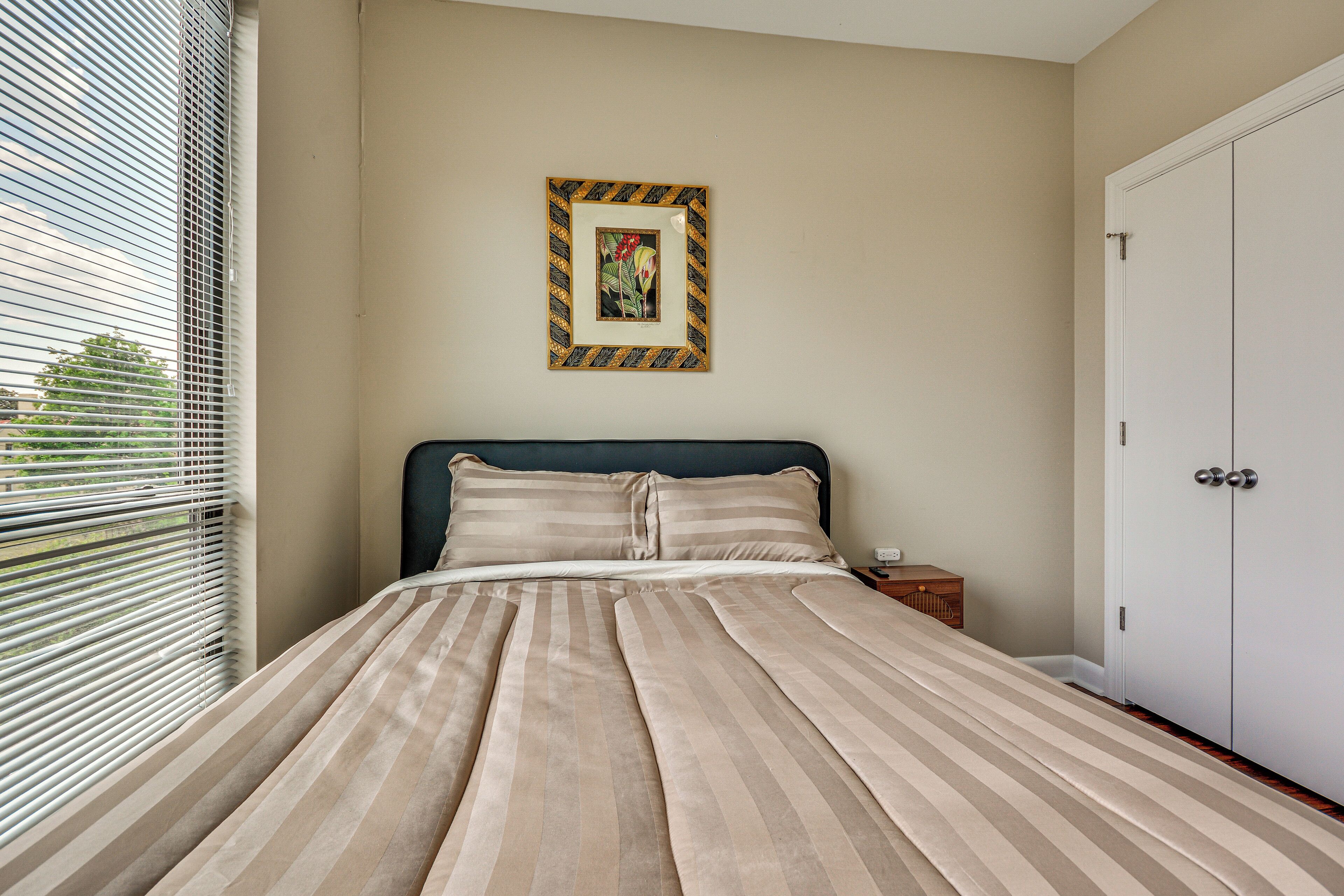A bedroom with a bed, a nightstand, a wardrobe, and a framed picture on the wall.