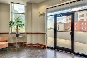 A hotel lobby with a large window, a potted plant, a small table, and a door leading outside. - Walkable Condo in Dtwn Greensboro! Extended Stay (Greensboro)