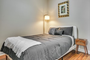 A bedroom with a bed, bedside table, lamp, and a framed picture on the wall. - Walkable Condo in Dtwn Greensboro! Extended Stay (Greensboro)