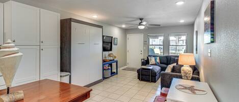 A spacious living area with a dining table, a sofa, and a ceiling fan.