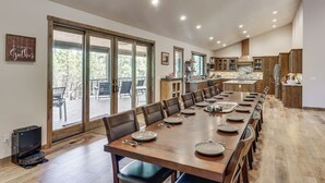 A spacious dining area with a long table, wooden chairs, and a view through large sliding glass doors to an outdoor deck. - Spacious Family Gem w/ Patio, 3 Mi to Rainbow Lake (Lakeside)