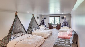 A room with four beds, each with a tent-like canopy, a window with a view, and a small table with chairs. - Spacious Family Gem w/ Patio, 3 Mi to Rainbow Lake (Lakeside)