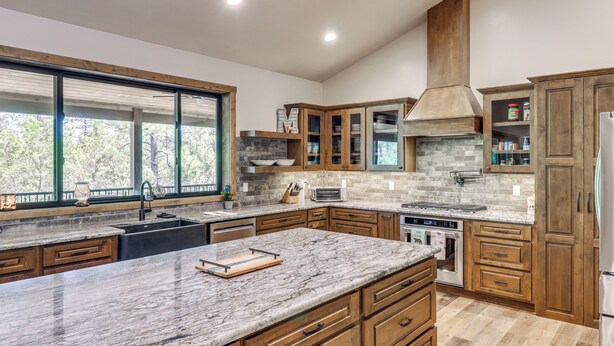 A modern kitchen with wooden cabinets, a large island, and a built-in oven. - Spacious Family Gem w/ Patio, 3 Mi to Rainbow Lake (Lakeside)