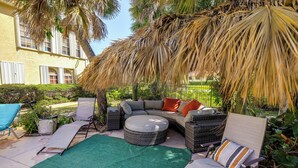 An outdoor seating area with a sofa, chairs, and a green mat. - Steps to Sand! Pet-friendly Home in Fort Pierce (Fort Pierce)