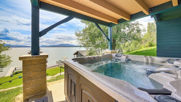 A hot tub under a covered patio with a view of a lake and mountains. - Stunning Sandpoint Lakefront Home: Hot Tub + Dock (Sandpoint)