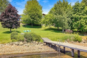 A serene park with a wooden deck, stone pathway, and a small bridge over water.