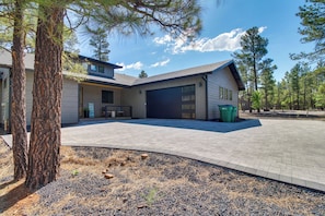 A modern two-story house with a garage, a paved driveway, and a landscaped yard with pine trees. - Modern Luxury in Torreon w/ HOT Tub! (Show Low)