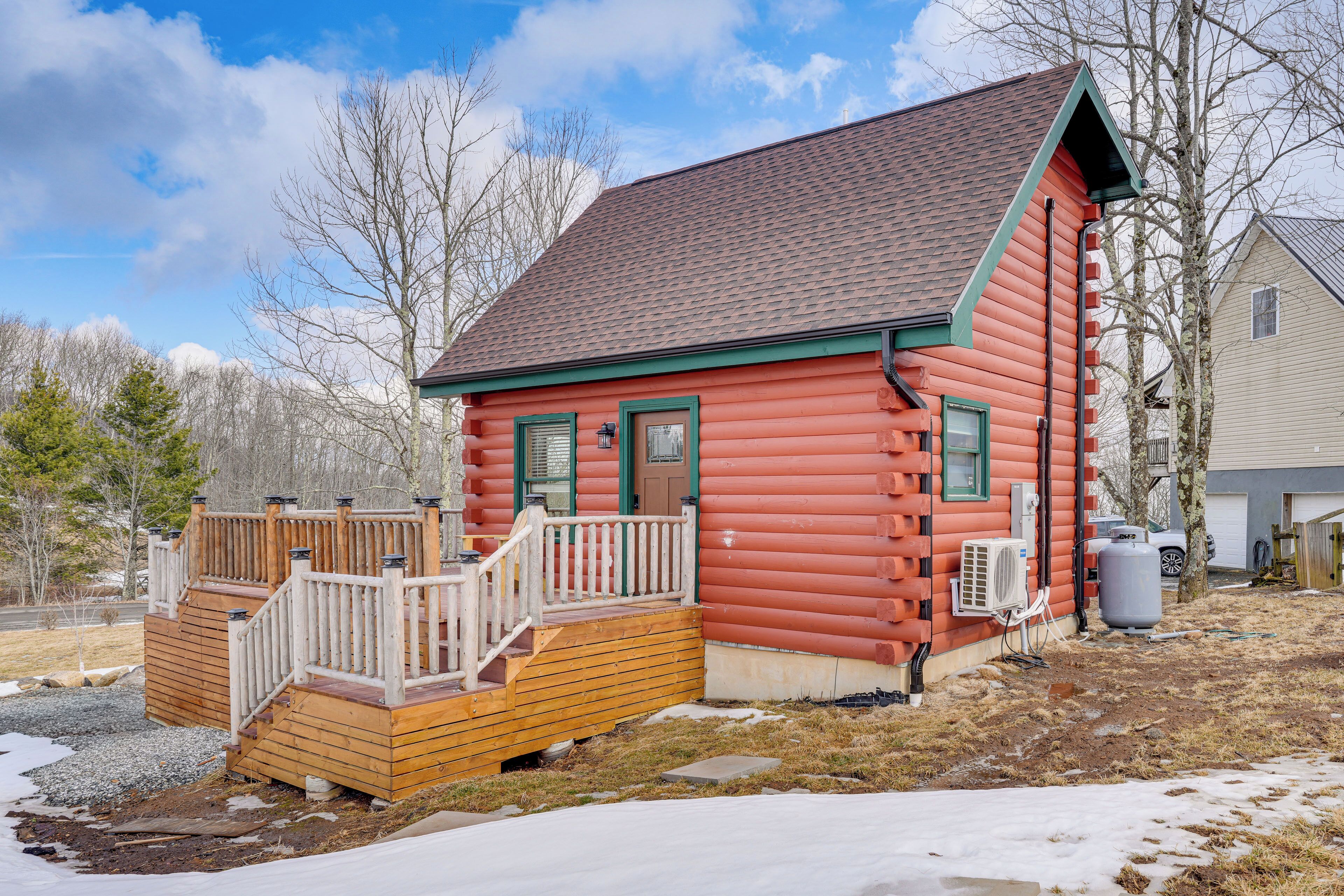 A log cabin with a wooden deck, a front door, and a chimney.