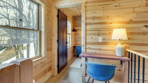 A wooden cabin interior with a desk, chair, lamp, and a door leading to another room. - Handcrafted Tiny Home, Near Dtwn Boone (Boone)