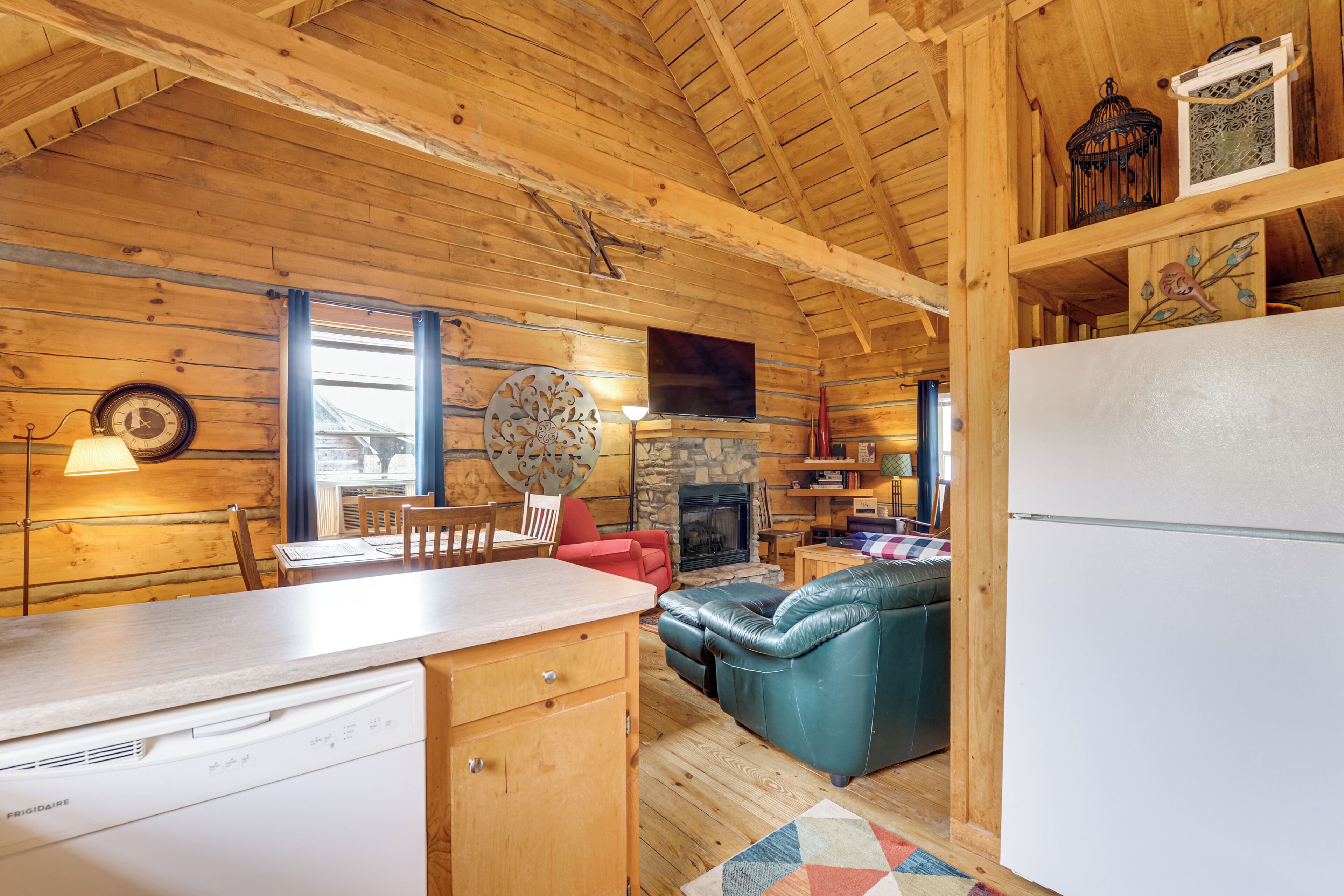 A wooden cabin interior with a kitchen, dining area, and living room.