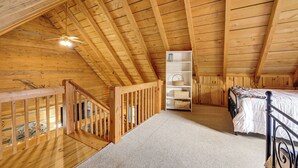 A wooden attic bedroom with a sloped ceiling, a bed, a white shelving unit, and a staircase. - 2 Mi to Blue Ridge Pkwy! Mtn Escape w/ Fireplace (Meadows Of Dan)