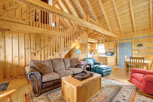 A wooden interior with a staircase, a sofa, a coffee table, and a dining area.