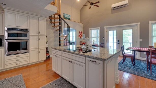A kitchen with white cabinetry, a built-in oven, a granite countertop, and a wooden staircase. - 'sunset Blue' Cabin Near Dale Hollow Lake (Byrdstown)