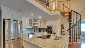A modern kitchen with white cabinetry, stainless steel appliances, a granite countertop, and a wooden staircase. - 'sunset Blue' Cabin Near Dale Hollow Lake (Byrdstown)
