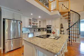 A modern kitchen with white cabinetry, stainless steel appliances, a granite countertop, and a wooden staircase. - 'sunset Blue' Cabin Near Obey River (Byrdstown)