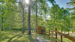 A wooden cabin with a stone pathway leading to it, surrounded by trees. - 'sunset Blue' Cabin Near Dale Hollow Lake (Byrdstown)