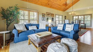 Ein geräumiges Wohnzimmer mit zwei blauen Sofas, einem Holztisch und einer großen Kübelpflanze.