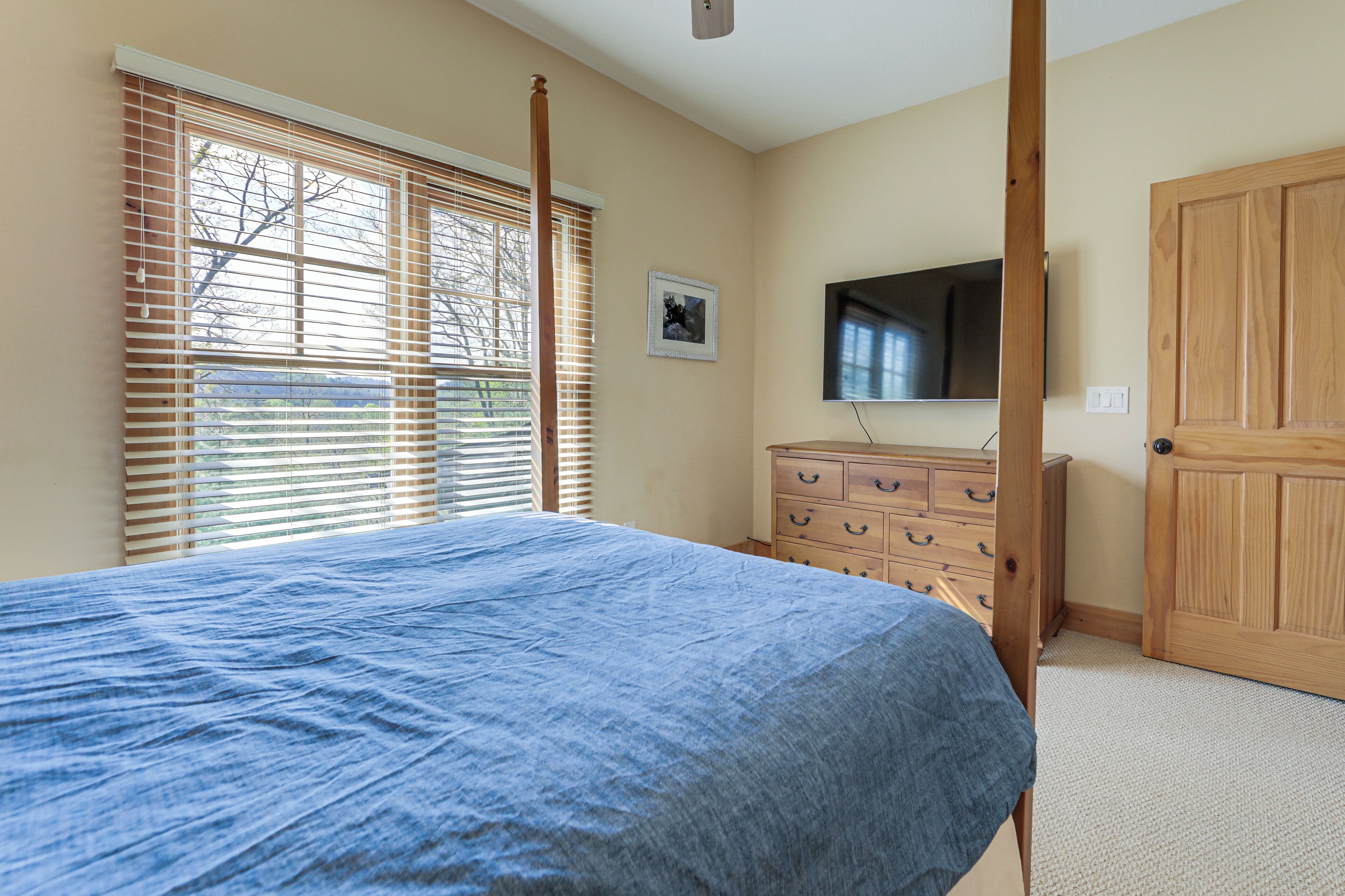 A bedroom with a bed, a dresser, a television, and a door.