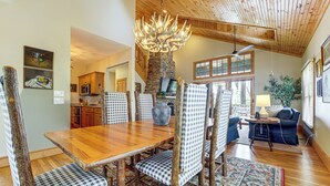 Ein Essbereich mit Holztisch, karierten Stühlen, einem Steinofen und einer Chandelier.
