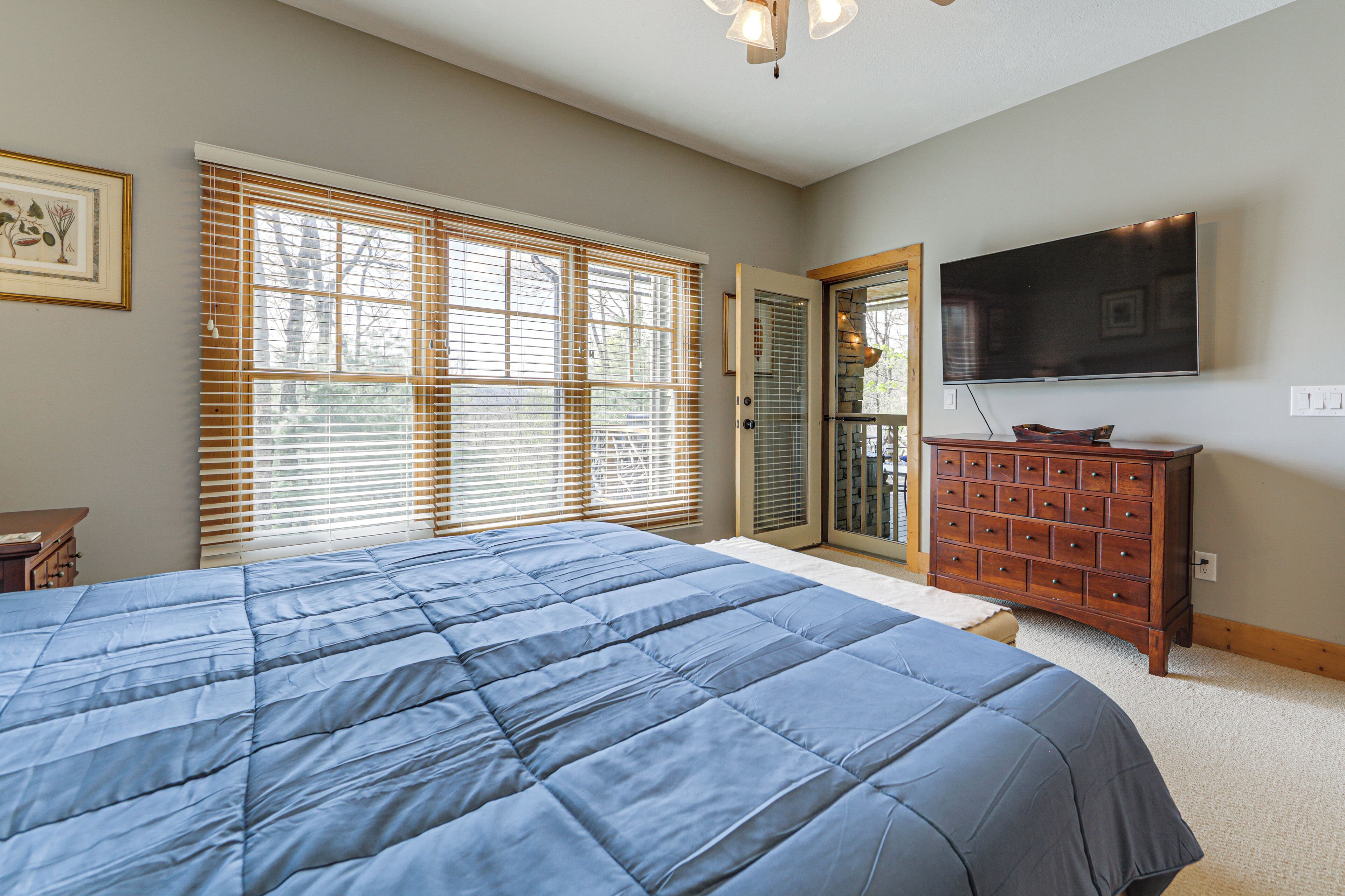A bedroom with a large bed, a dresser, a television, and a sliding glass door.