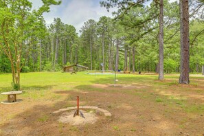 A forested area with a small cabin, a volleyball net, and a disc golf tee. - 2 Mi to Greers Ferry Lake Boat Ramp! Cozy Studio (Higden)