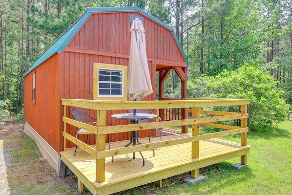 A wooden cabin with a porch, a table, and chairs.