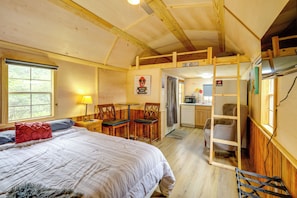 A cozy room with a bed, a desk, and a chair, wooden walls, and a loft area.