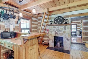 Una cocina rústica con vigas de madera, una chimenea de piedra y una isla de madera con fregadero.