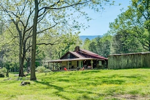 A rustic cabin with a porch, surrounded by a grassy field and trees. - Trout Stream Access! Rural Buchanan Cabin (Buchanan)