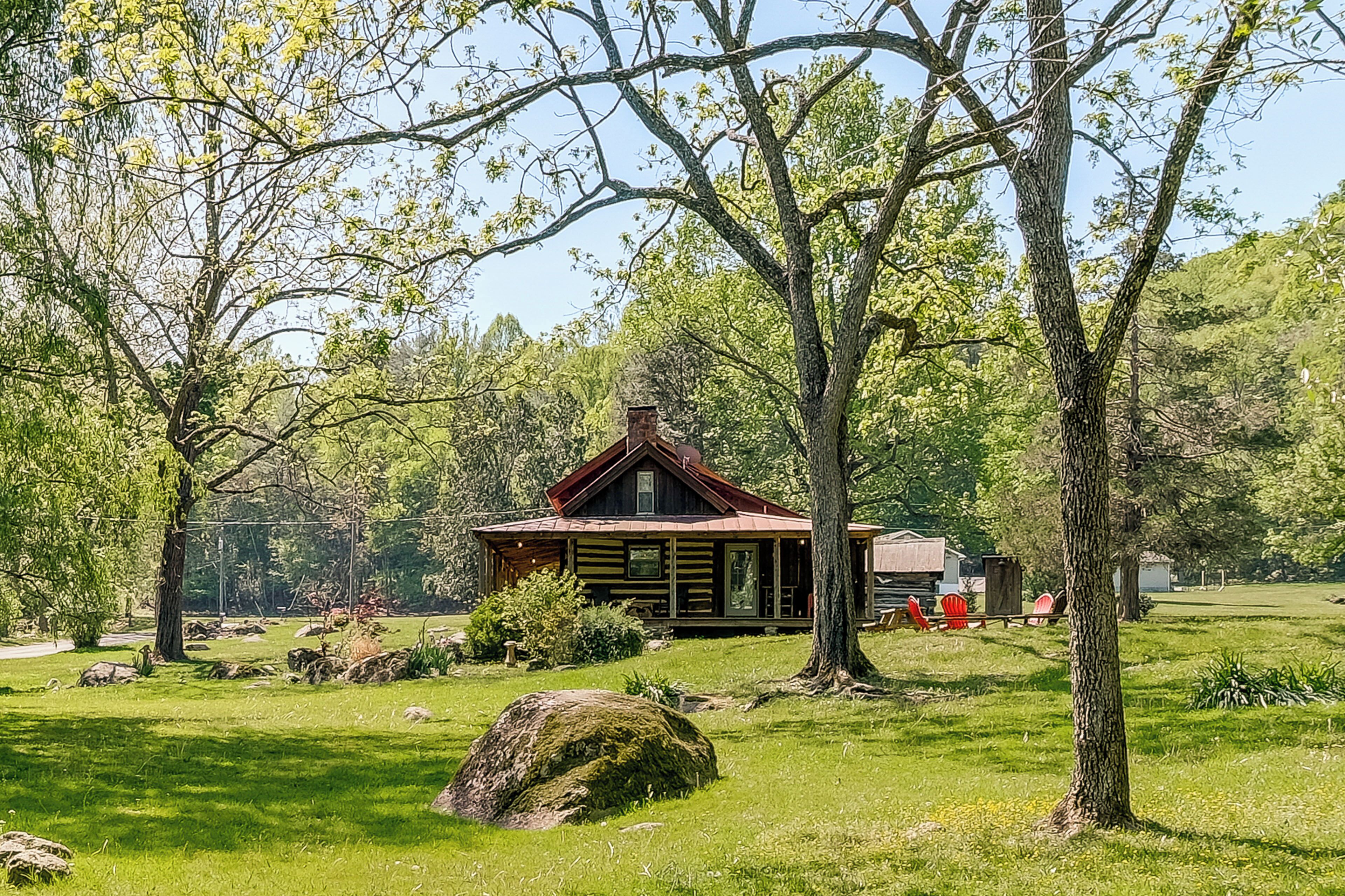A rustic cabin with a wooden exterior, surrounded by a grassy landscape and trees.
