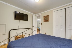 A bedroom with a bed, a television mounted on the wall, a door, and a small stool. - Walk to Dtwn Brevard! Mtn Escape w/ Fire Pit (Brevard)