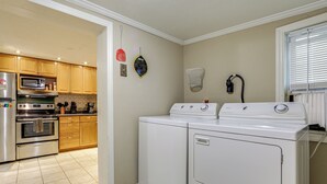 Een keuken met houten kastjes, een magnetron, een oven en een wasmachine.