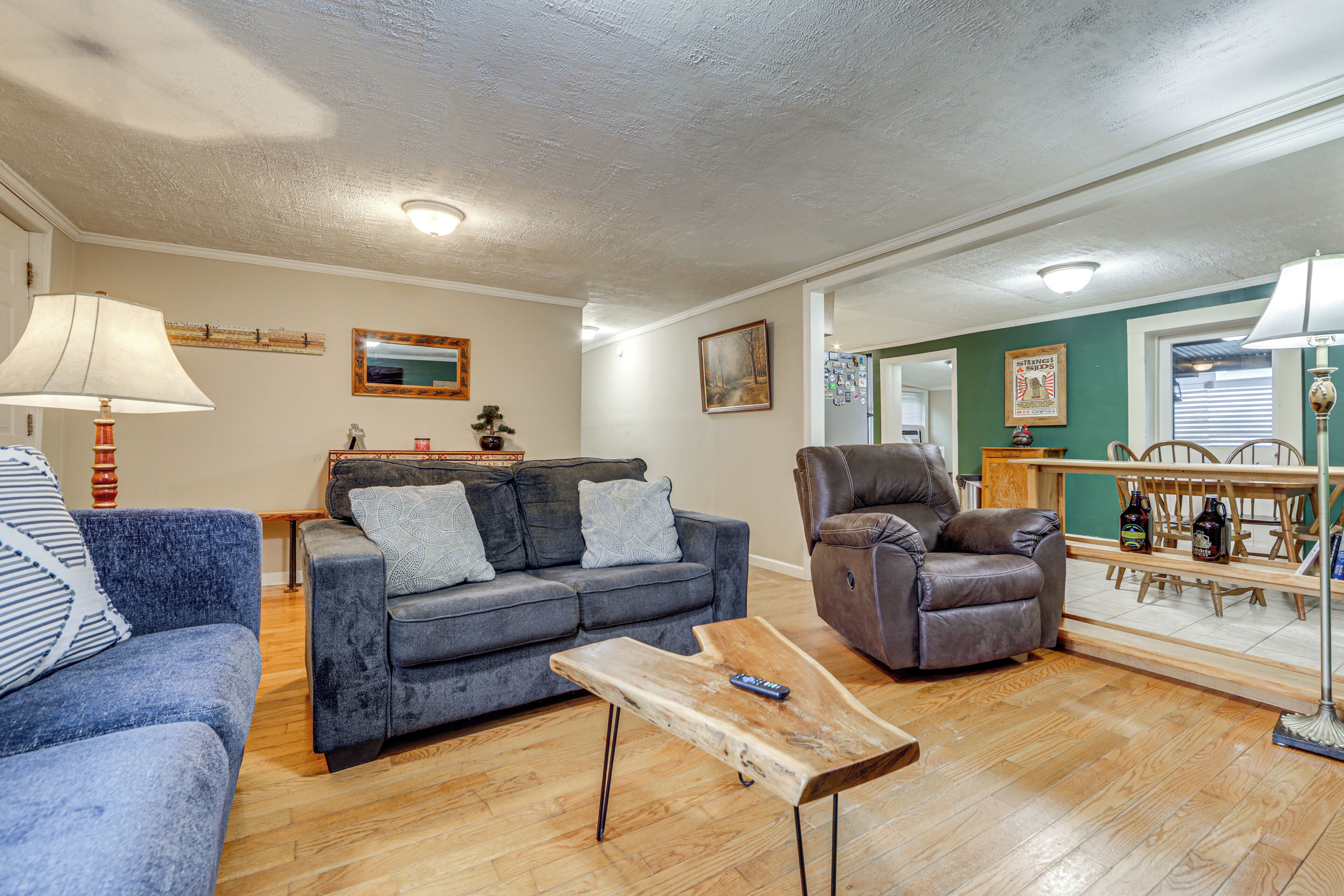 Un salon comprenant un canapé, une table basse, un fauteuil en cuir et un coin repas avec une table et des chaises.