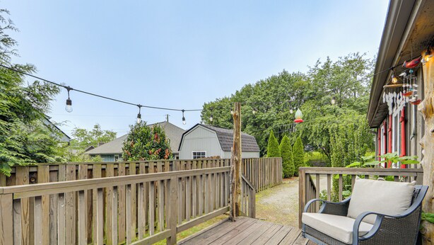 Een houten terras met een rieten schommelstoel en een lichtslingering.