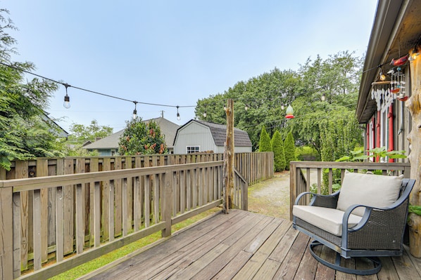 A wooden deck with a wicker rocking chair and a string of lights. - Walk to Dtwn Brevard! Mtn Escape w/ Fire Pit (Brevard)