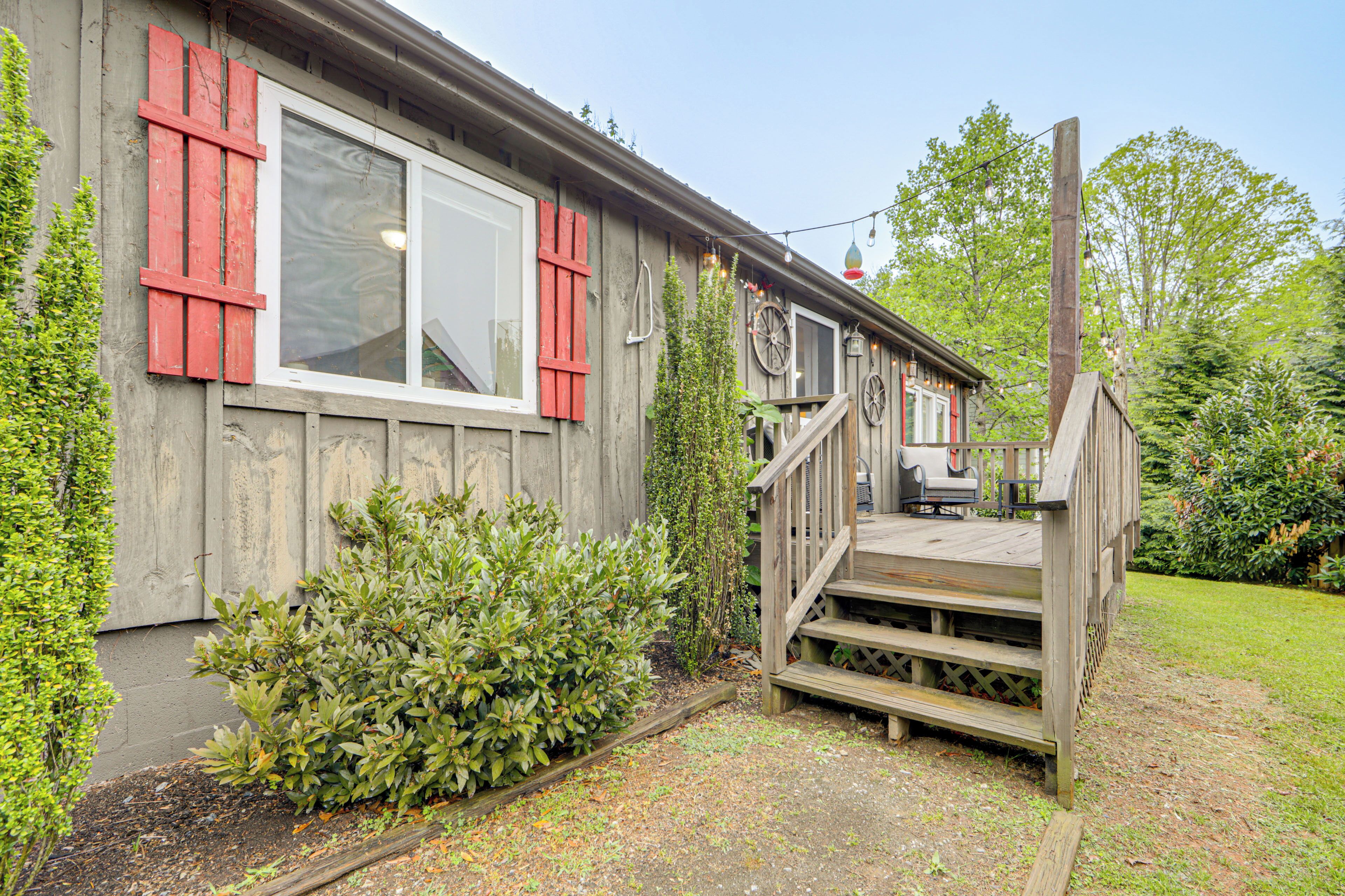 A wooden house with a porch, a staircase, and a garden.