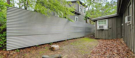 A backyard with a metal fence, a small shed, and a fire pit area.
