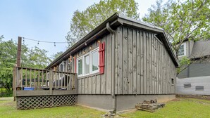 Een houten hut met een terras, een raam met rode luiken en een pad van stenen dat naar de ingang leidt.