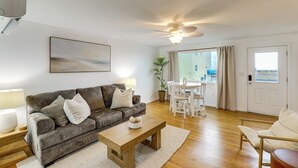 A living room with a sofa, coffee table, and a dining area with chairs and a table. - Steps to Shore! Family-friendly Getaway in Hampton (Hampton)