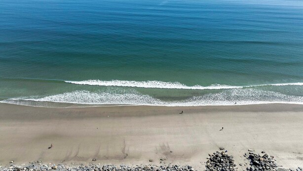 A beach with waves, a sandy shore, and scattered rocks. - Steps to Shore! Family-friendly Getaway in Hampton (Hampton)