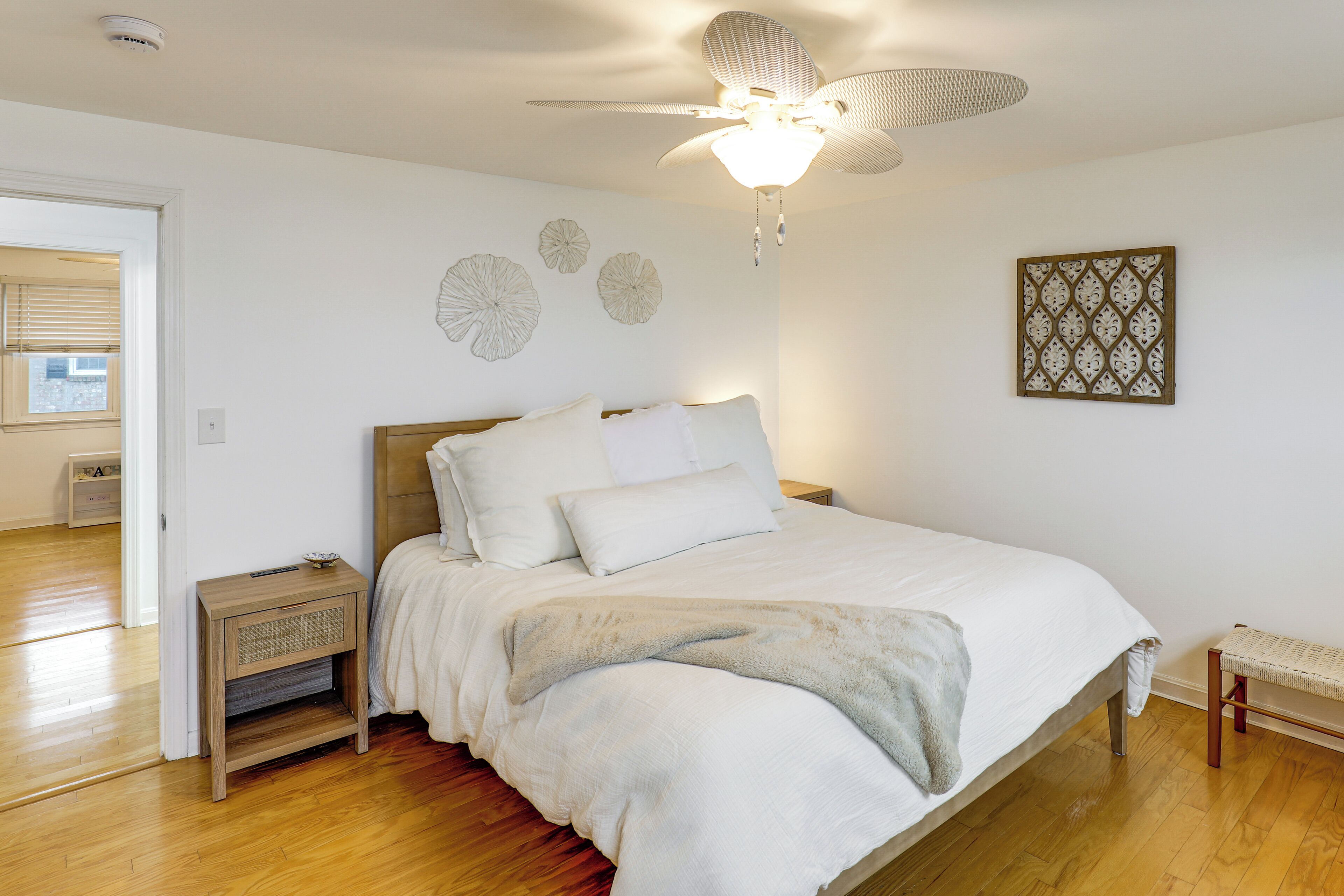 A bedroom with a bed, bedside table, and a ceiling fan.