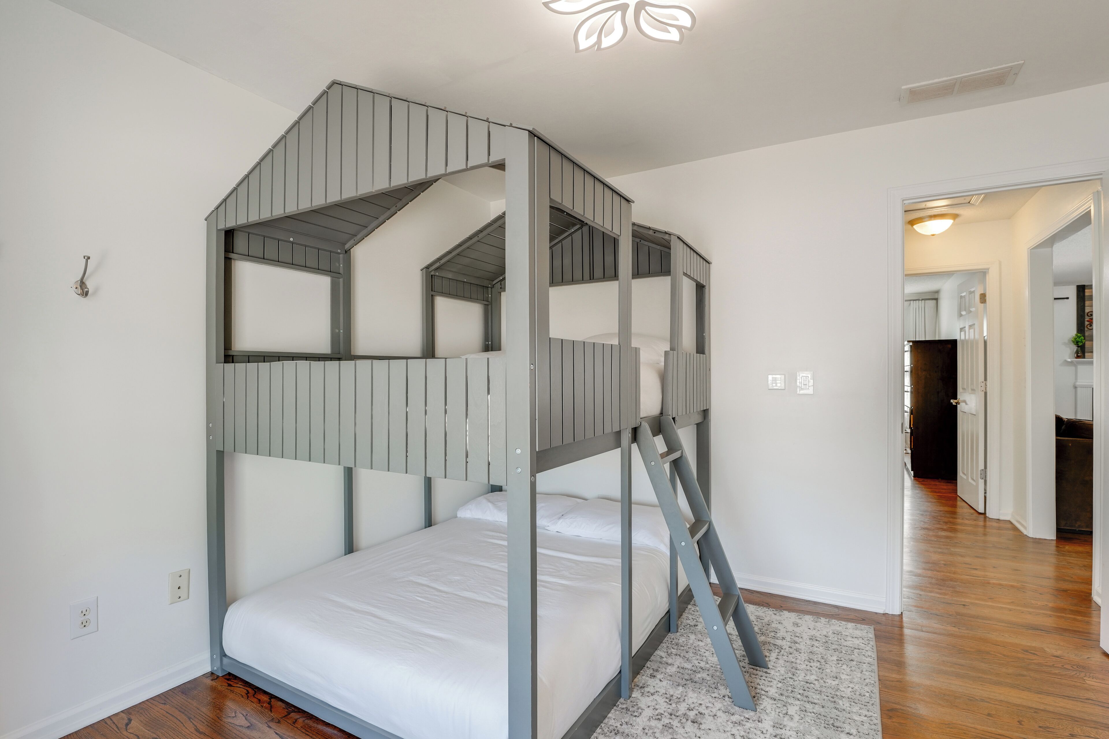 Ein Etagenbett mit einer Leiter, eine weiße Wand und ein Holzboden.