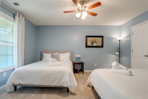 A bedroom with two beds, a ceiling fan, a nightstand, a lamp, and a framed artwork on the wall. - Modern 6BR Haven With Playroom, Gym, Deck (Cartersville)