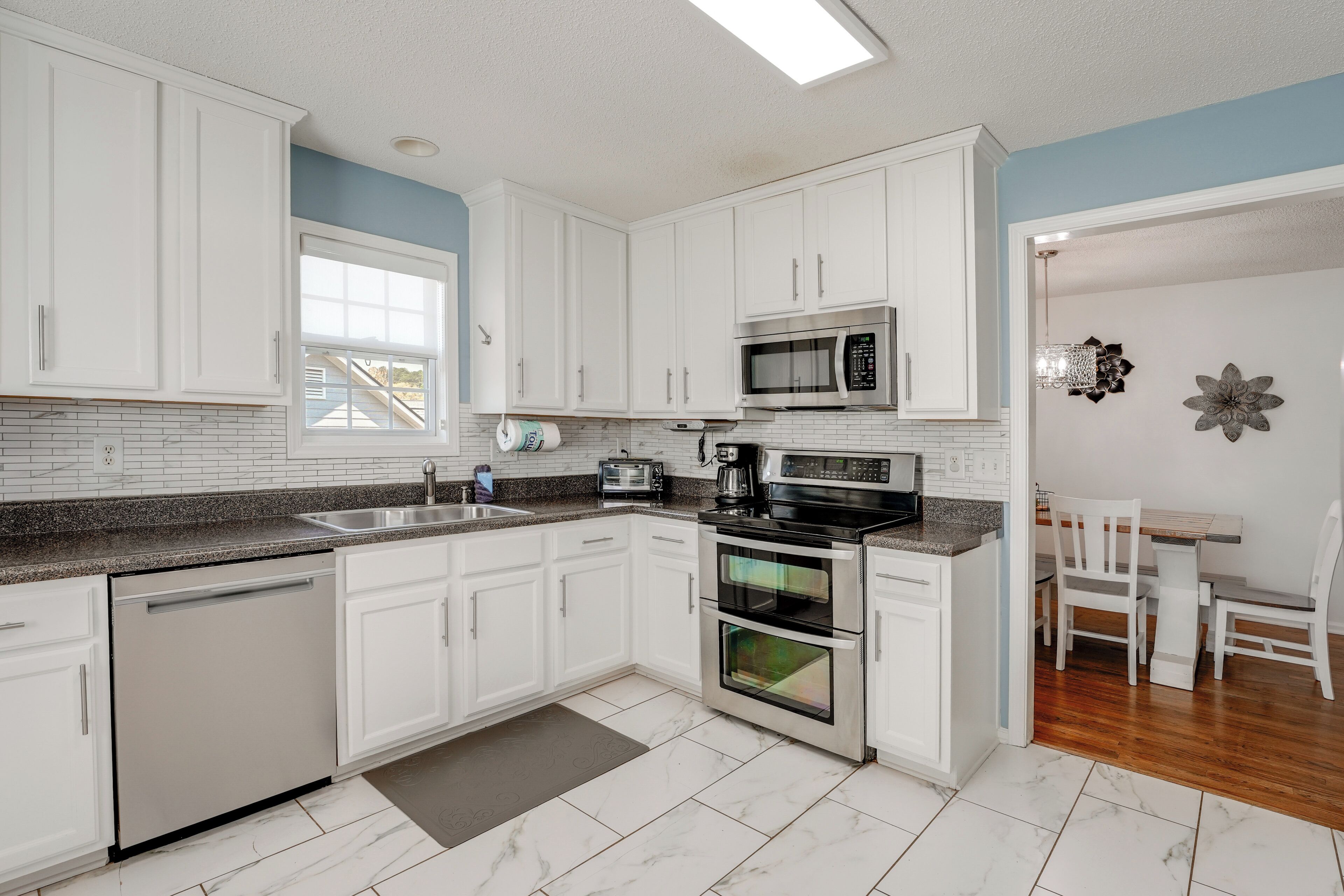 A modern kitchen with white cabinets, a microwave, a dishwasher, and a double oven.