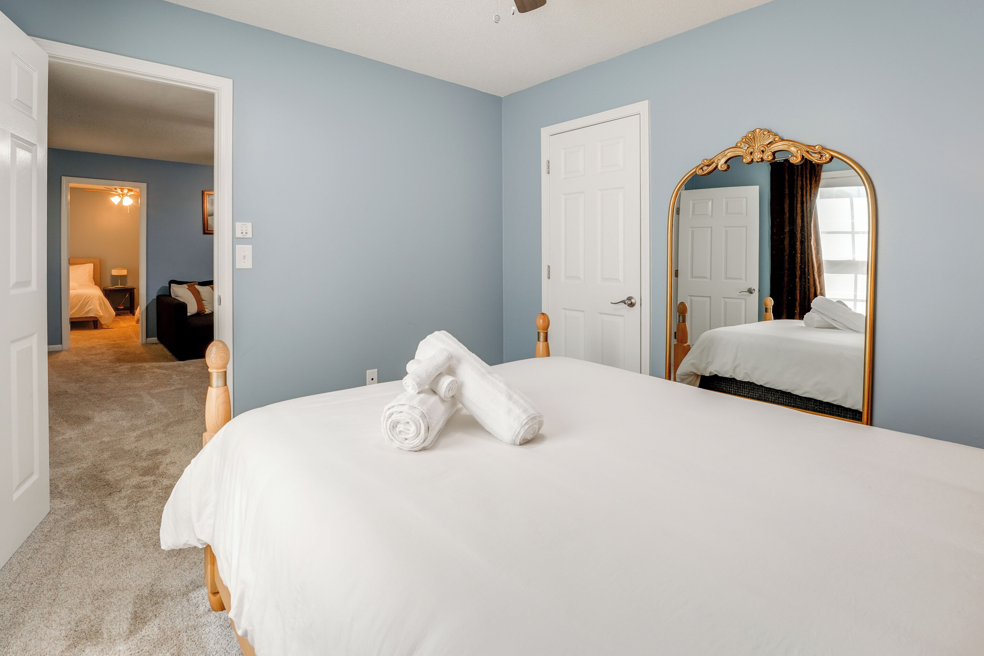 Een slaapkamer met een bed, een spiegel en een deur.