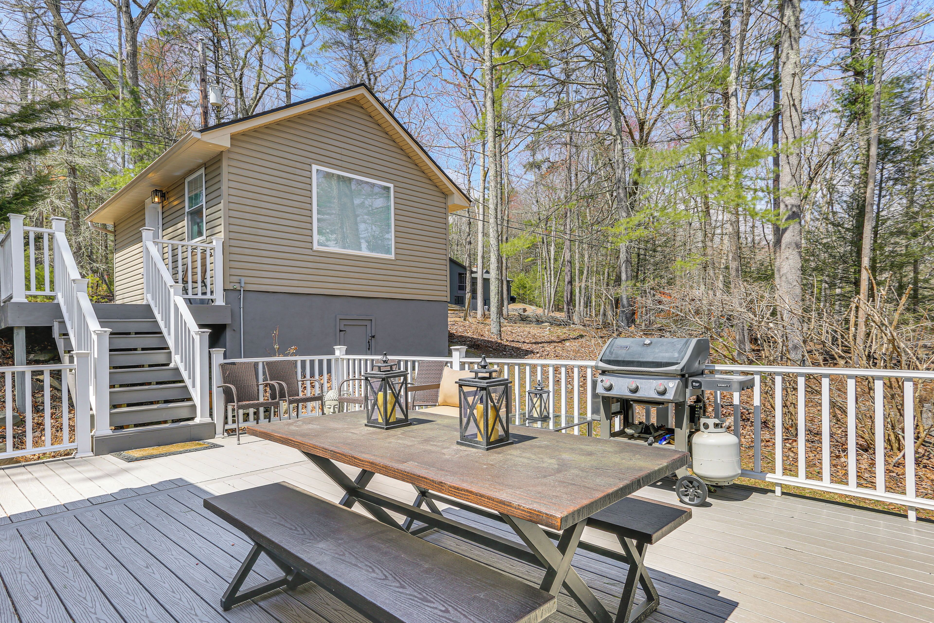 A wooden deck with a picnic table, barbecue grill, and lanterns.